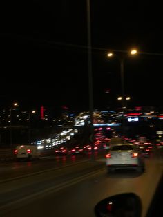 cars driving down the highway at night with city lights in the backgrouund