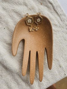 a brown hair comb with two small flowers on it's head and gold ear clips