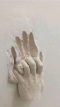 a plaster hand is attached to a wall with white paint on it's fingers