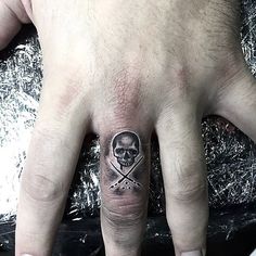 a man's hand with a skull and crossbones tattoo on the middle finger