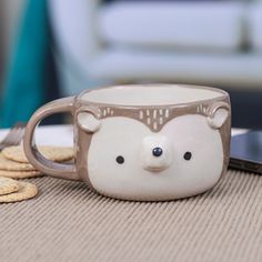 a mug with a bear face on it sitting next to crackers