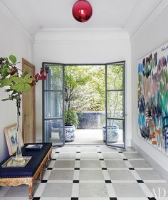 an open door leading to a patio with potted plants on the table and vases