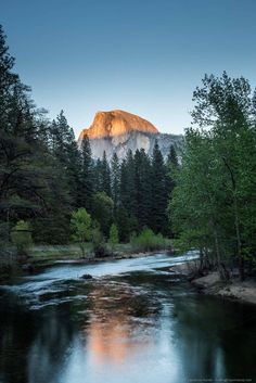 a river running through a forest with a mountain in the background