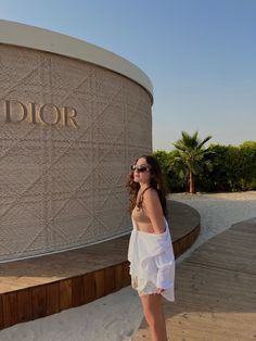 a woman standing in front of a sign that says dior on the side of a building