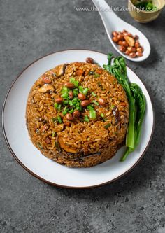 a white plate topped with rice covered in nuts and veggies