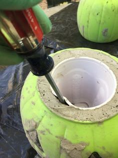 a person using a drill to fix a hole in a large green pot with cement on it