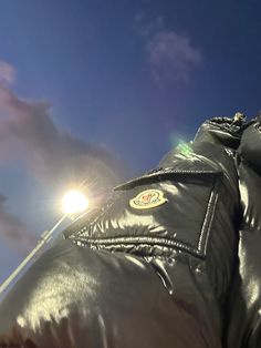 a person wearing a leather jacket and holding a cell phone up to their ear with the sky in the background