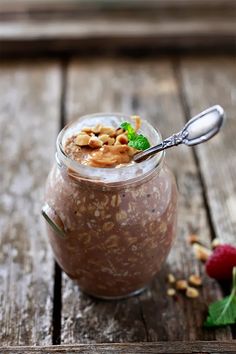 a jar filled with food sitting on top of a wooden table next to a spoon