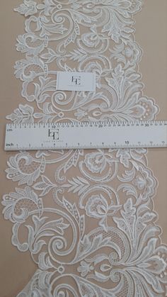 the white lace is measuring on top of the tablecloth with a ruler next to it