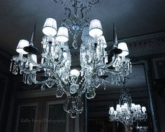 a chandelier hanging from the ceiling in front of a mirror with lights on it