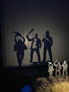 three silhouettes of people holding baseball bats in front of a building with hay and straw bales