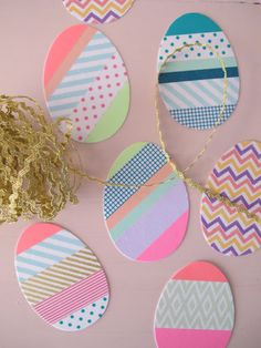 easter eggs painted in different colors and patterns on a pink surface next to gold foil