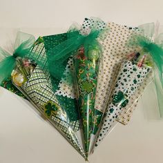 four green and white paper bags with shamrocks on them, tied to organ netting