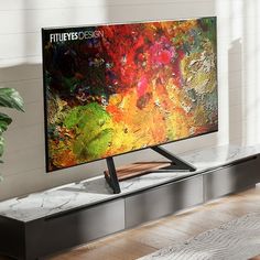 a flat screen tv sitting on top of a wooden table next to a potted plant