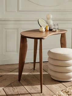 a wooden table with a mirror on top of it next to pillows and a stool