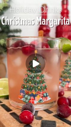 a christmas margarita with cranberries and limes on the table next to it