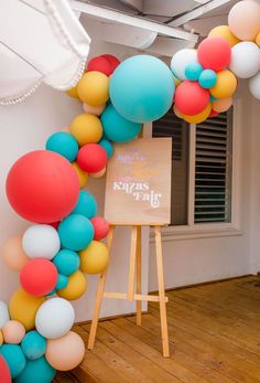 an arch made out of balloons in the shape of a letter on a easel