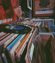 an old record player sitting on top of a table full of records in front of a poster