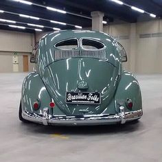 an old green car parked in a garage