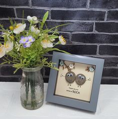 a vase filled with flowers next to a picture frame