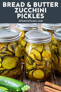 several jars filled with pickles on top of a wooden table next to some vegetables