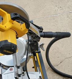 a yellow and black machine is sitting on the ground with its hose connected to it