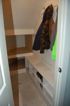 an open closet with several coats hanging on the wall and shoes in the bottom shelf