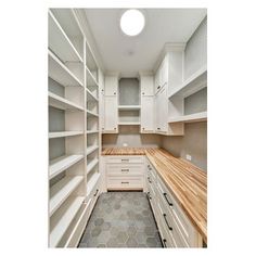 an empty walk - in closet with white cabinets and wood counter tops on the floor