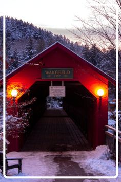 the covered bridge is lit up with red lights and snow on the ground around it