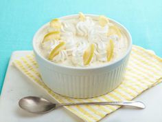 a white bowl filled with food sitting on top of a table next to a spoon