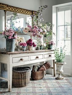 a white table topped with lots of flowers next to a mirror on top of a wall