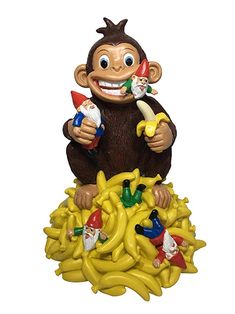 a monkey figurine sitting on top of bananas with an assortment of toys around it