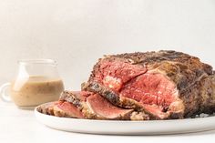 a large piece of meat sitting on top of a white plate next to a cup