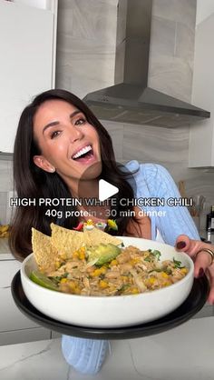 a woman holding a plate with food on it in the middle of her hands and laughing