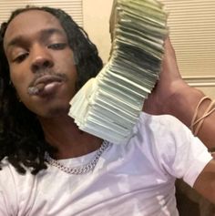 a man with dreadlocks is holding up a stack of papers in front of his face