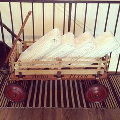 a wooden wagon filled with white blankets on top of a striped rug