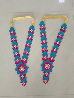 two pieces of beaded jewelry are on the floor next to each other, one is pink and blue