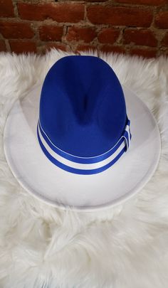 Make a statement from the crown on down!   This comfy classic is an all-season, breathable fedora, sporting the classy pinched crown, and ribbon adjustable straps with a blue and white fitted band. Material: 65% Cotton 35% polyester Size Fits: 53cm to 57cm in circumference Sorority Ornaments, Women Fedora, Fedora Women, Tan Hat, Mens Fedora, Flat Brim Hat, Wide Brim Fedora, Painted Hats, Stylish Hats