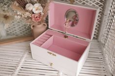 a pink and white jewelry box sitting on top of a table next to a vase with flowers