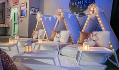 a room filled with lots of white furniture covered in blankets and pillows next to candles