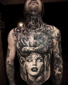 a man with many tattoos on his chest and head is standing in front of a mirror