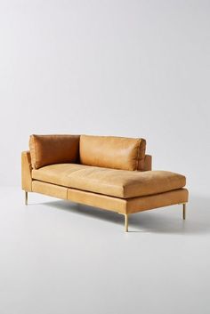 a tan leather couch sitting on top of a white floor next to a wooden frame