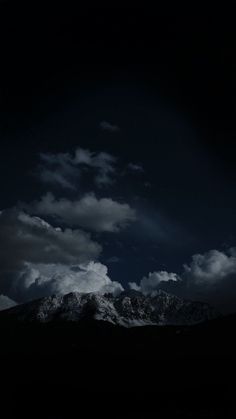 the dark sky is filled with clouds and mountains