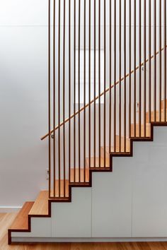 a wooden stair case next to a white wall