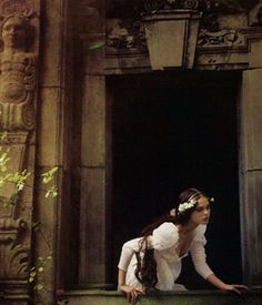 a woman sitting on the ledge of an old building