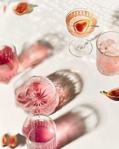 some glasses and figurines are sitting on a table with pink liquid in them