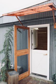 an open door to a building with a tree in the doorway and another plant next to it