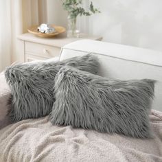 two gray furry pillows sitting on top of a bed