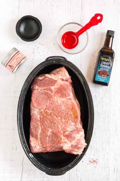 raw meat in a skillet with spices and seasoning next to it on a white table