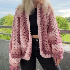 a woman with blonde hair wearing a pink crocheted cardigan